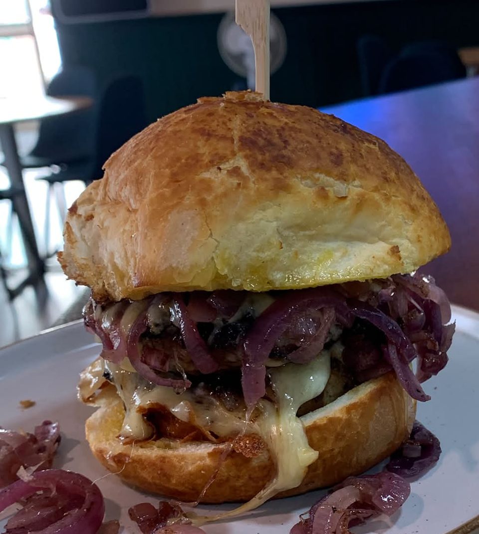 Signature Sausage Bap with homemade sausage patties, melted cheese and caramelised red onion